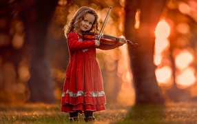Маленькая девочка в красном платье со скрипкой в руках 