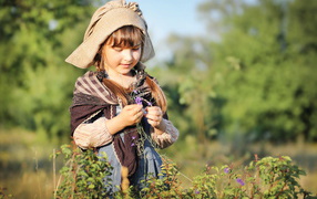Маленькая девочка в костюме собирает травы