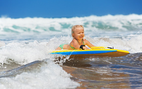 Little girl in the sea on a surfboard