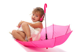 Little girl is sitting in a pink umbrella on a white background