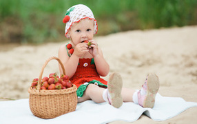 Маленькая девочка сидит с корзиной спелой клубники