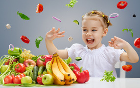 Little girl playing with vegetables and fruits in the kitchen