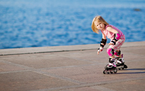 Маленькая девочка катается на роликах на побережье