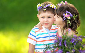 Little girl with a bouquet of wildflowers kisses a boy