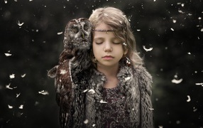 Little girl with closed eyes with an owl on her shoulder