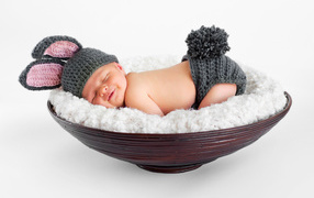 Маленький спящий грудной ребенок в вязаном костюме зайчика