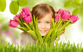 Little smiling brown-haired girl with a bouquet of pink tulips