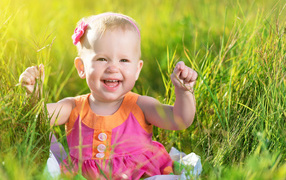 Little smiling girl sitting in green grass
