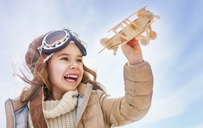 Little smiling girl with an airplane in hands