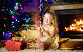 Long-haired blonde girl with lollipops near Christmas tree