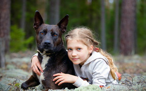Милая голубоглазая девочка с большой черной собакой