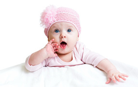 Грудная голубоглазая девочка в розовой шапке на белом фоне