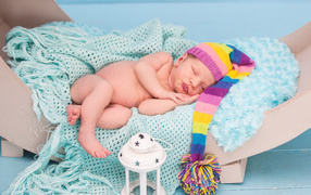 Спящий грудной ребенок в большой вязаной шапке