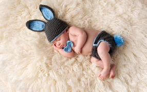 Sleeping baby in a knitted hare costume
