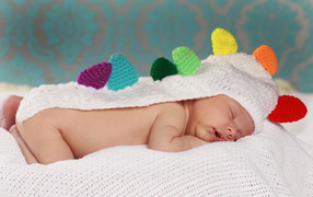 Sleeping baby in a white knitted cape