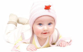 Улыбающийся голубоглазый малыш в розовой шапке