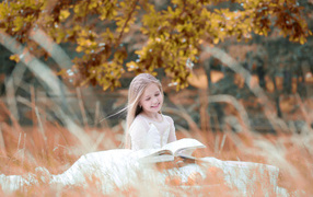 Smiling girl in white dress reading a book