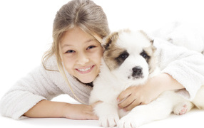 Улыбающаяся девочка с щенком алабая на белом фоне