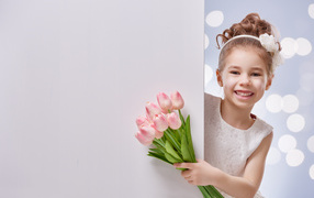 Улыбающаяся маленькая девочка с букетом розовых тюльпанов