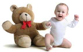 Улыбающийся малыш с большим плюшевым медведем на белом фоне
