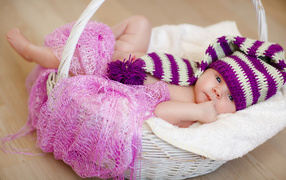 The baby in a beautiful knitted hat lies in the basket