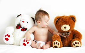 Младенец сидит с двумя большими плюшевыми медведями