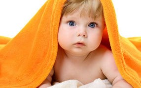 Голубоглазый малыш лежит под оранжевым покрывалом