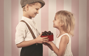 Мальчик дарит девочке коробку шоколадных конфет