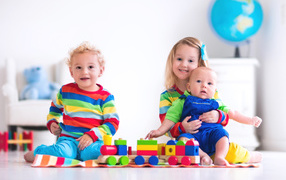 Три ребенка играют с игрушечным поездом