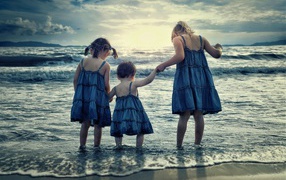 Три маленькие девочки стоят в воде на берегу моря