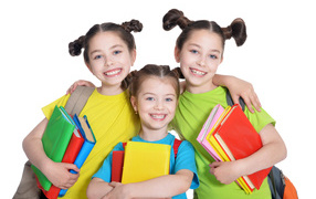 Три маленькие улыбающиеся девочки с книгами на белом фоне