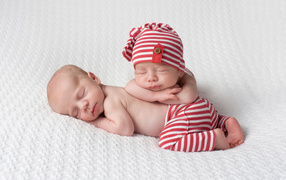 Two cute baby sleeping in striped suits