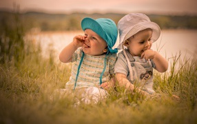 Two cute kids in green grass in summer
