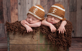 Два милых спящих малыша в забавных вязаных шапках