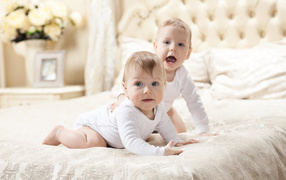 Two funny babies lie on the bed