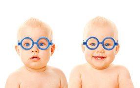 Two funny babies with blue glasses on a white background