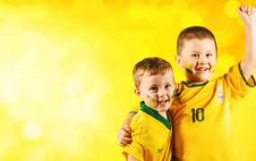 Два маленьких мальчика в спортивной форме на желтом фоне