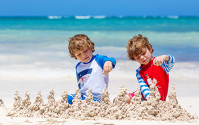 Two little boys playing with sand on the beach