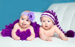 Два маленьких забавных младенца в красивых фиолетовых костюмах