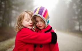 Две маленькие девочки обнимают друг друга 
