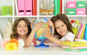Две маленькие девочки школьницы с глобусом  в руках