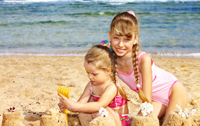 Две маленькие девочки гуляю на песке на пляже