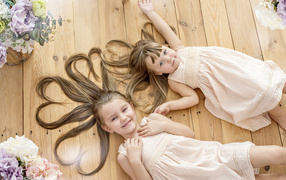Две маленькие девочки с длинными волосами лежат на полу