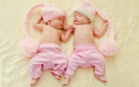 Два спящих грудных ребенка в розовых костюмах