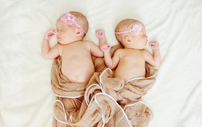 Два спящих младенца с розовыми цветами на голове