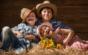 Two smiling boys and a girl in straw hats
