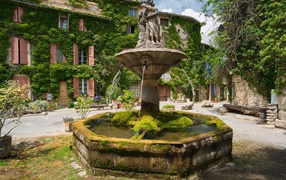 Старинный покрытый мхом фонтан на площади Сеньон, Франция