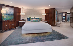 Большая кровать с белым покрывалом в спальне в коричневых тонах