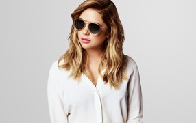 Actress Ashley Benson in black glasses on a gray background