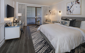 Спальня с большой кроватью и телевизором на стене